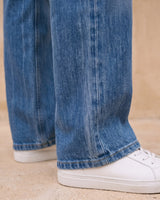 Sloane Straight Leg Jeans in blue — close-up of the straight-leg hem over sneakers