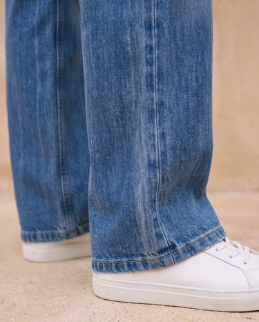 Sloane Straight Leg Jeans in blue — close-up of the straight-leg hem over sneakers