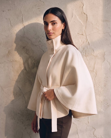 The Lorenne cape coat in white — side three-quarter view on model