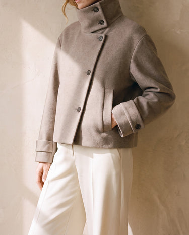 Three-quarter view of the Ottilie Funnel Jacket in taupe with hand in the slit pocket