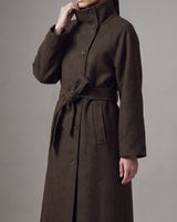 Henrietta Coat in brown, three-quarter view with hand at the funnel collar