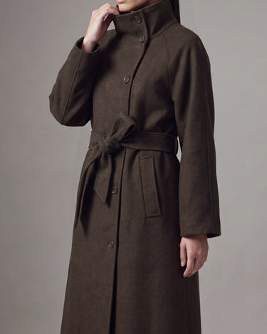 Henrietta Coat in brown, three-quarter view with hand at the funnel collar