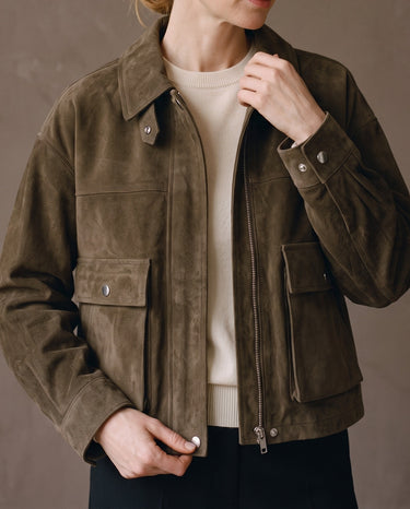 Juniper Suede Utility Jacket in olive worn over a cream knit, half zipped with hand at the collar