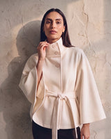 The Lorenne cape coat in white — on model with hand at the stand collar
