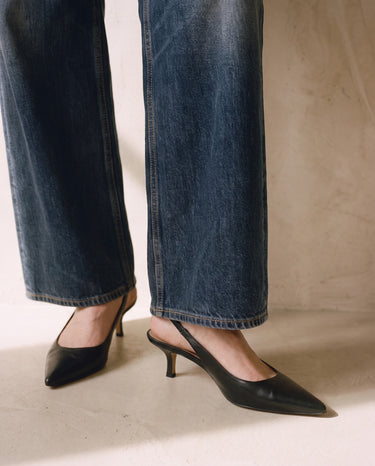 Close-up of the Delphine Wide Leg Jeans hems falling over black slingback heels