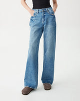 Model wearing Hallie Jeans with hands in the front pockets, black rib tank