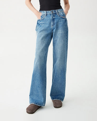 Model wearing Hallie Jeans with hands in the front pockets, black rib tank