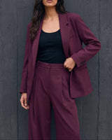 The Aliya Burgundy Blazer Set in burgundy — blazer and trousers, front view with hand in pocket on model