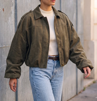 Model wearing the olive green Astor Faux Suede Bomber Jacket over a cream top and light blue jeans, front view