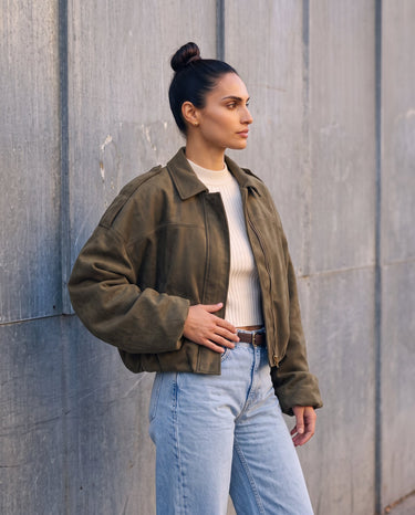 Model in the olive green Astor faux suede bomber, three-quarter view showing the cropped boxy fit