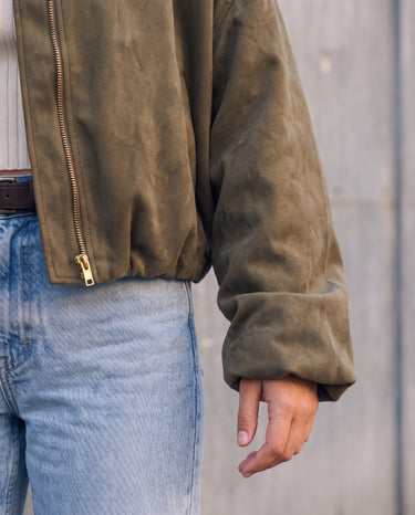 Detail of the Astor bomber's sleeve and gold zip in olive green faux suede