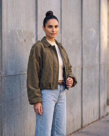 Full-length view of the olive green Astor Faux Suede Bomber Jacket styled with jeans