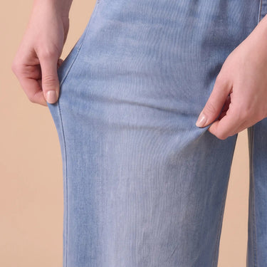 Hands stretching the soft knit denim of the Isla jeans
