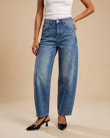 Barrel Jeans in blue — mid-rise barrel-leg denim styled with a white tank, hand in pocket, front view on model