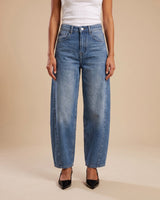 Barrel Jeans in blue — straight-on front view on model with a white tank and black heels