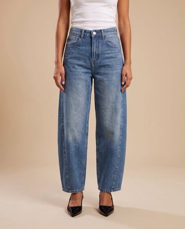 Barrel Jeans in blue — straight-on front view on model with a white tank and black heels