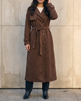 Model wearing the brown Bexley Trench Coat belted at the waist over black trousers, front view