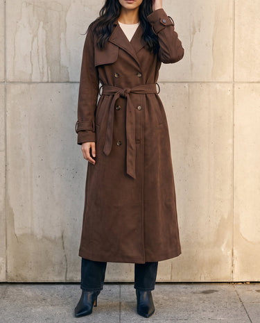 Model wearing the brown Bexley Trench Coat belted at the waist over black trousers, front view
