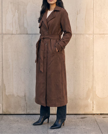 Model with hands in pockets wearing the brown Bexley Trench Coat, three-quarter front view