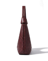 The Siren Woven Bag in burgundy, side profile view showing the narrow depth and knotted strap