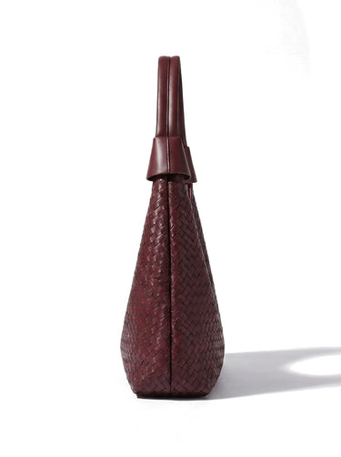 The Siren Woven Bag in burgundy, side profile view showing the narrow depth and knotted strap