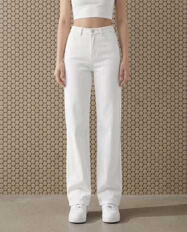 Model wearing the white Cali Jean, front view showing the high rise, button and zip fly and relaxed wide leg, styled with a white crop top and sneakers