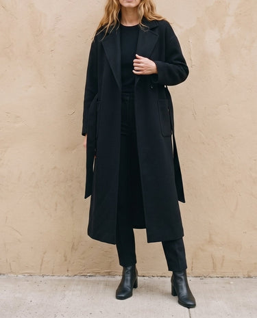 The Caroline Tie Waist Coat in black — longline belted coat worn open, front view on model