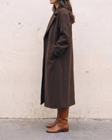 The Chocolate Maxi Coat in chocolate brown — longline coat, side view on model