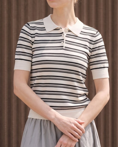 Cosetta Polo in white — front view on model against a ribbed brown wall