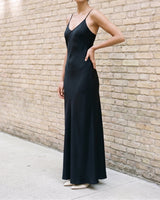 Model wearing the black Eclipse Satin Dress, front view showing the V neckline, bias-cut body and floor-length flared hem