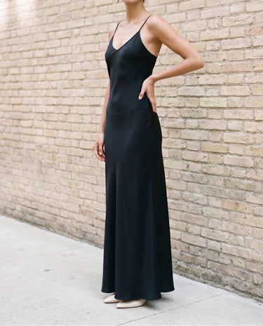 Model wearing the black Eclipse Satin Dress, front view showing the V neckline, bias-cut body and floor-length flared hem