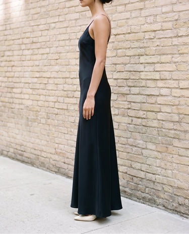 Side view of the black Eclipse Satin Dress showing the fluid bias-cut drape falling to the floor