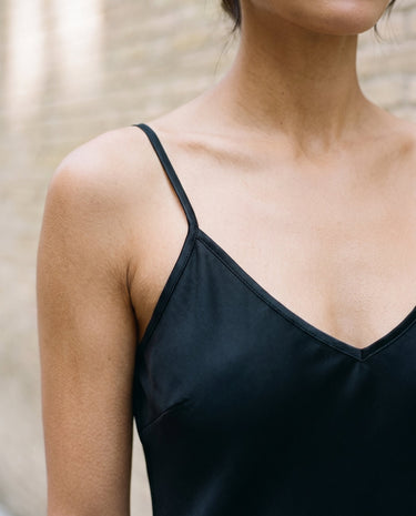 Close-up of the black Eclipse Satin Dress showing the fine shoulder strap, V neckline and satin sheen