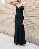Three-quarter view of the black Eclipse Satin Dress showing how the bias cut skims the waist and hip