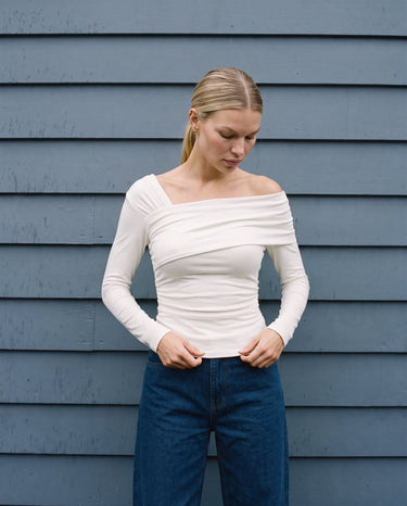 Model wearing the white asymmetric shoulder top with wide-leg jeans, front view – Moriel Heritage