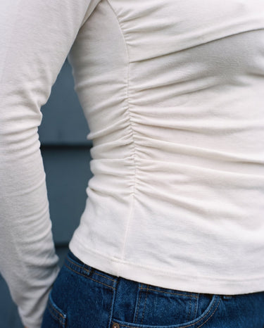 Close-up of the ruched side seam on the white top – Moriel Heritage