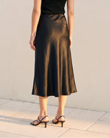 Model wearing black satin midi skirt, back view showing flared hem – Moriel Heritage