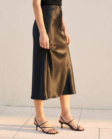 Model wearing black satin midi skirt, three-quarter side view – Moriel Heritage