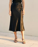 Model wearing black satin midi skirt, cropped front view showing drape – Moriel Heritage