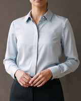 Model wearing the light blue satin-look shirt tucked into black trousers, close front view