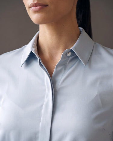 Close-up of the shirt's point collar and single collar button in light blue satin-look fabric