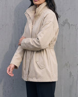 Side view of the light khaki Halden Coat showing the stand collar and hip-length hem