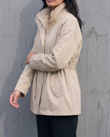 Side view of the light khaki Halden Coat showing the stand collar and hip-length hem