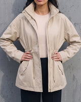 Model in the light khaki Halden Coat over a cream top and black trousers, front view