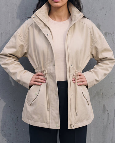 Model in the light khaki Halden Coat over a cream top and black trousers, front view