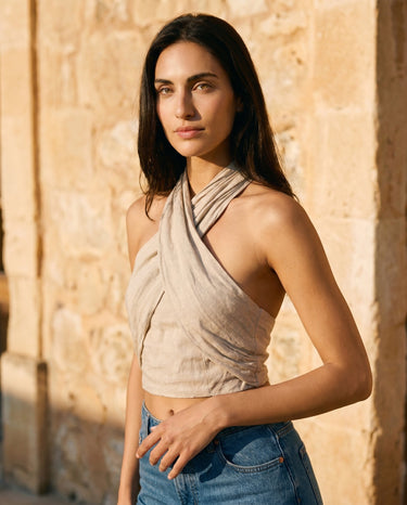 Model wearing the beige linen crossover halter crop top with blue jeans, front view – Moriel Heritage