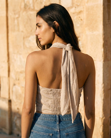 Back view of the beige linen halter top showing the tie-back neck and shirred back panel – Moriel Heritage