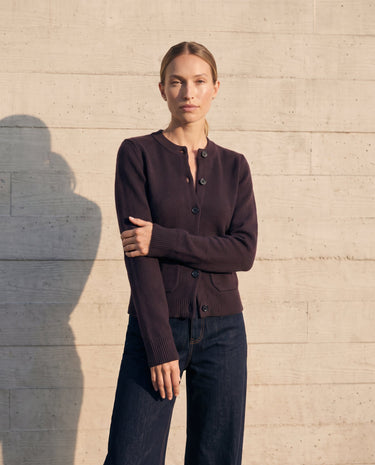 The Frankie Knit Cardi in aubergine — turned view on model showing the flared ribbed cuffs