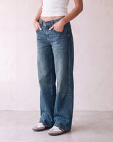 Harlow Low Rise Jeans in washed blue — three-quarter view on model, hands in pockets
