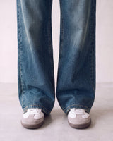 Harlow Low Rise Jeans in washed blue — close-up of the wide hems pooling over sneakers